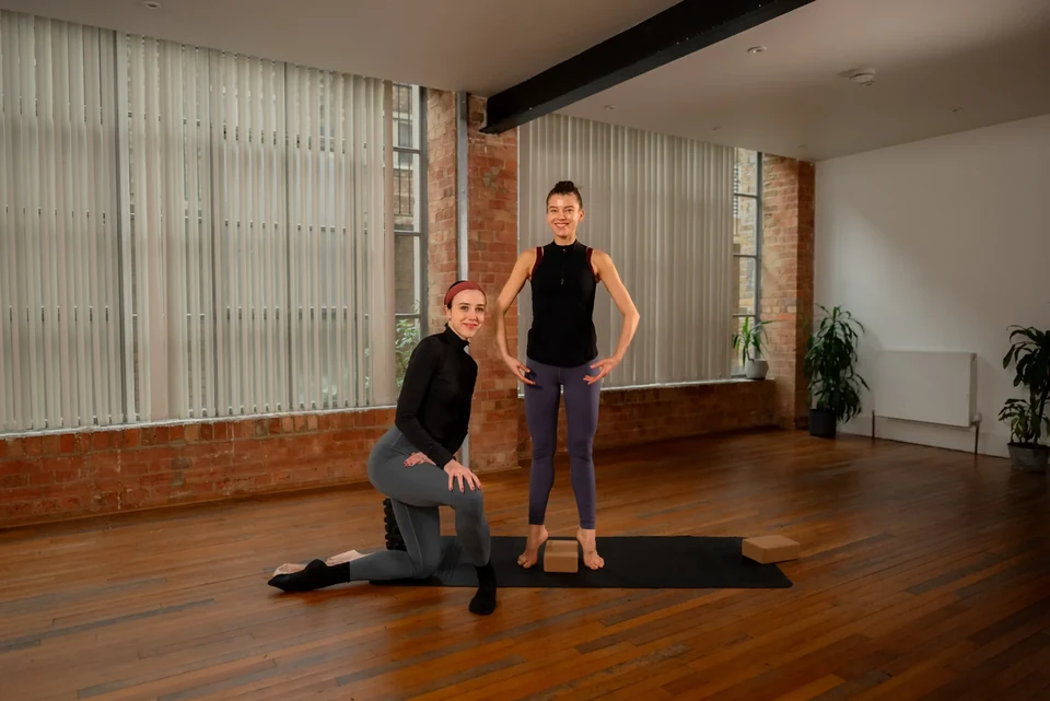 Two dancers in a studio setting practicing ballet