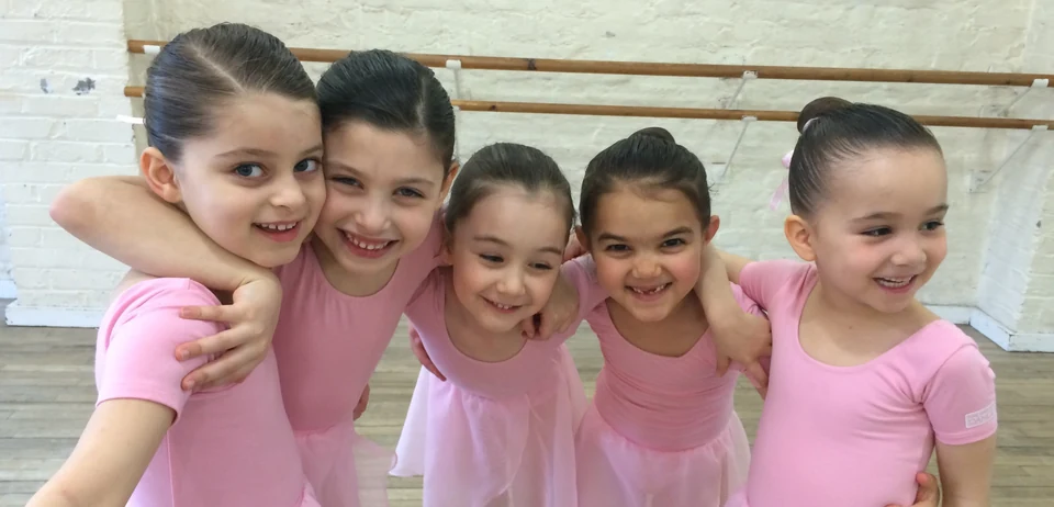 Five young ballet dancers in pink costumes