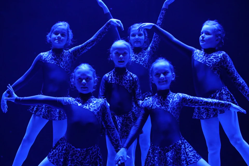 Group of dancers in blue lighting performing a pose