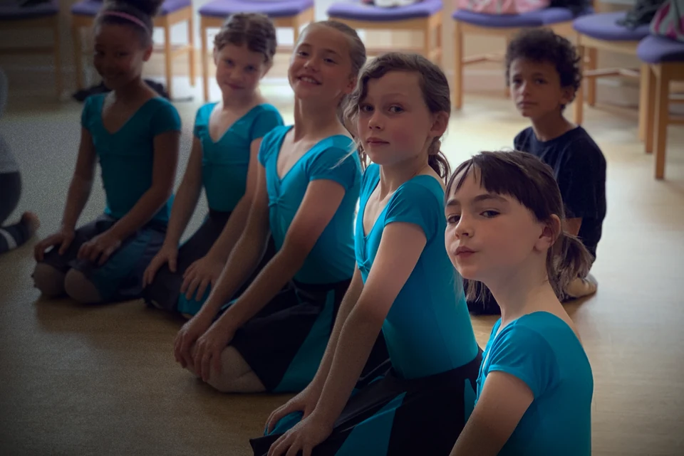 Group of young dancers in blue costumes sitting