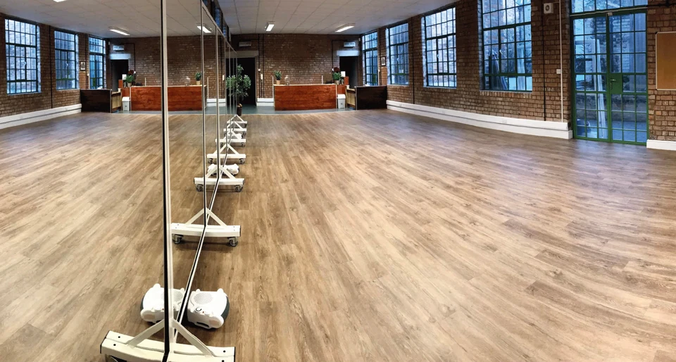 Dance studio with wooden floor and large windows