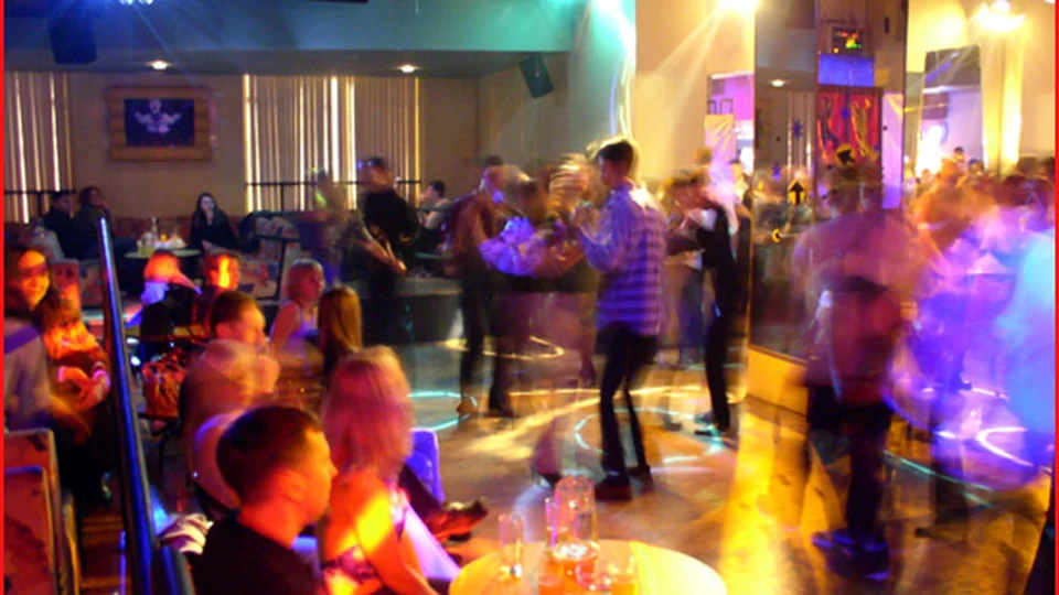 People dancing in a lively venue with colorful lights