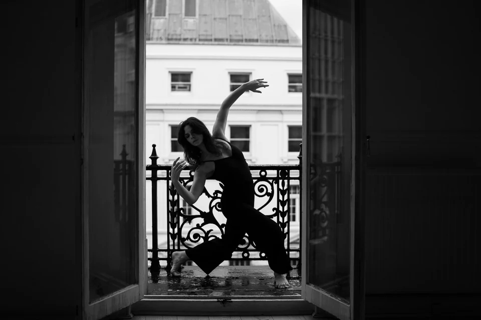 Dancer performing in a doorway with a balcony view