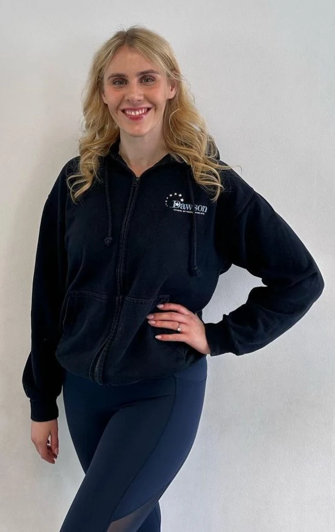 Woman in black hoodie posing against white wall