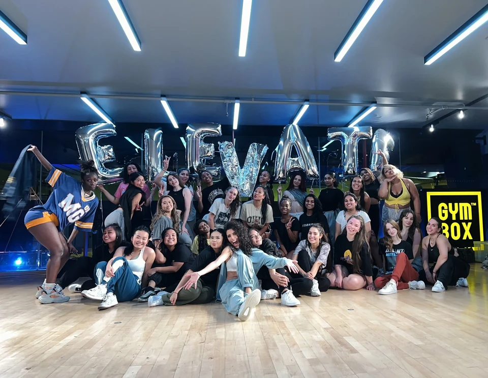 Group of dancers posing with 'ELEVATE' balloons