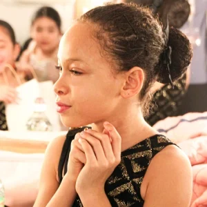 Young girl in ballet attire with hands clasped