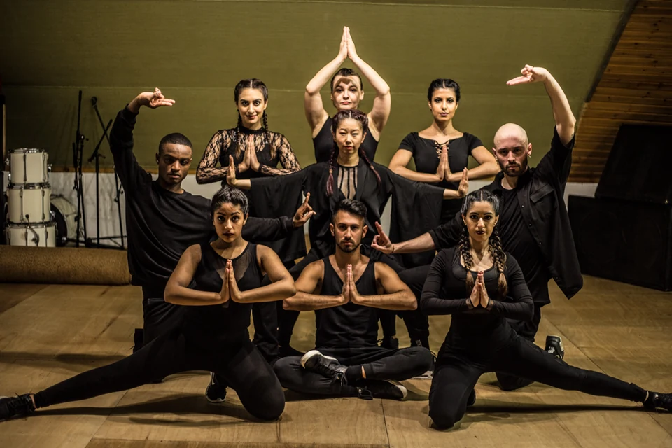 Group of dancers in black attire performing a pose