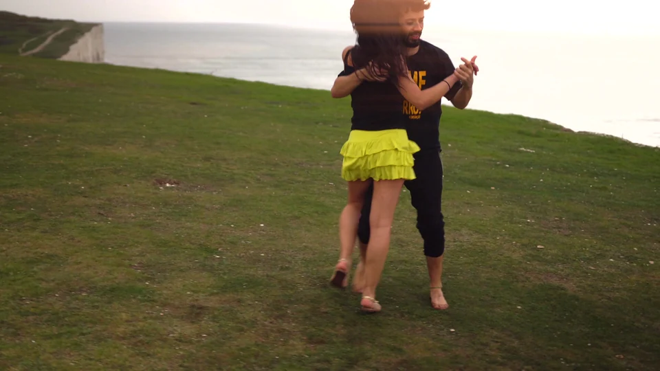 Couple dancing on grass near cliffs by the sea