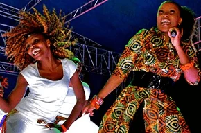 Two women dancing on stage with vibrant outfits