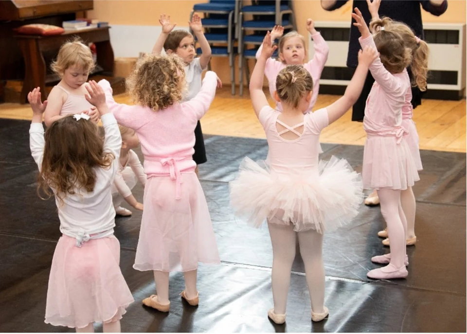 Children in ballet attire dancing in a studio