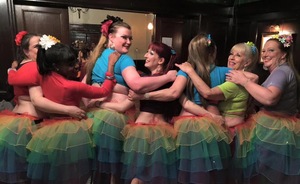 Group of dancers in colorful tutus embracing each other