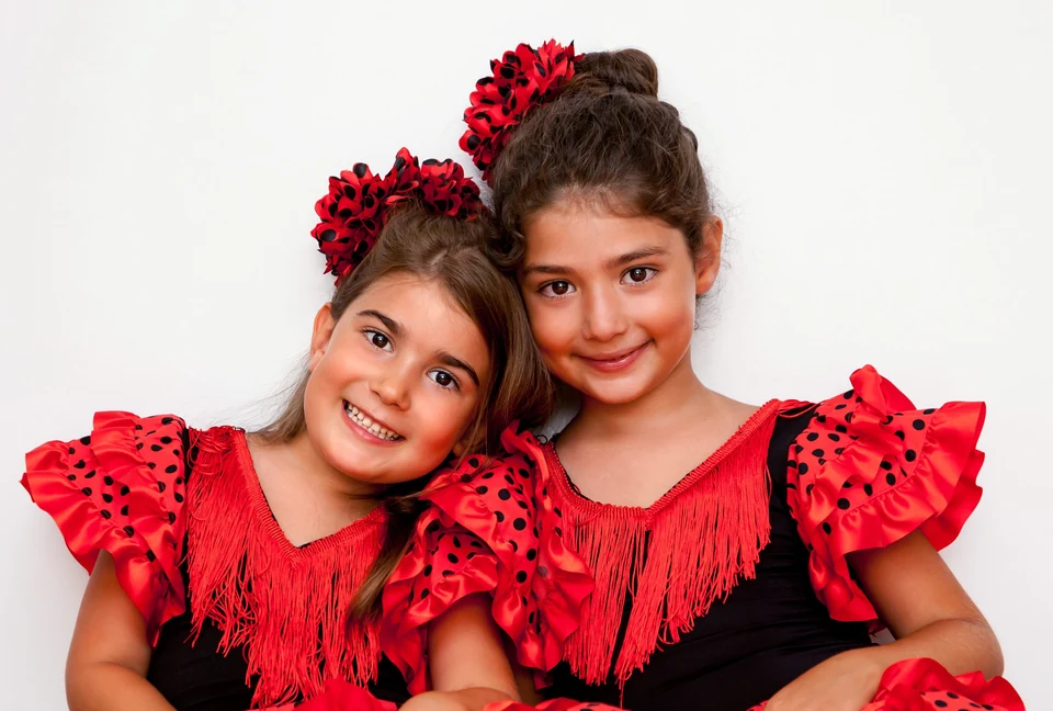 Two girls in red flamenco dresses smiling