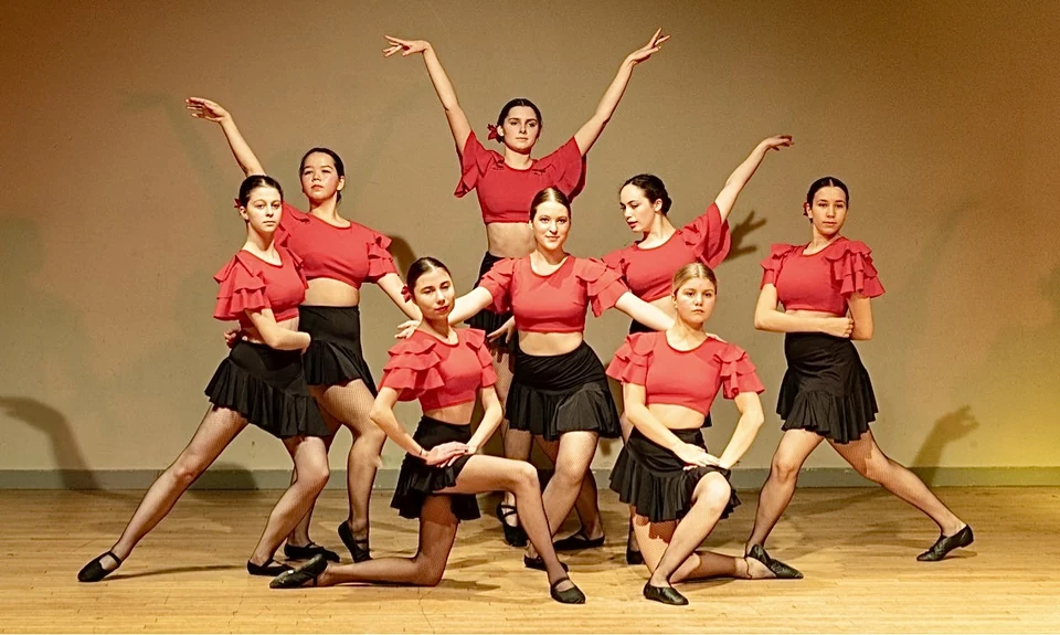 Group of dancers in red tops and black skirts