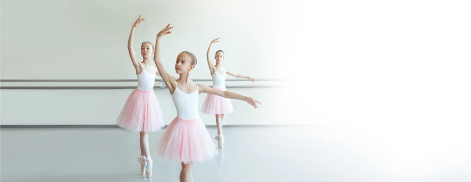 Three young ballet dancers in tutus practicing