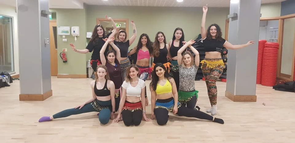 Group of women in belly dance attire posing indoors