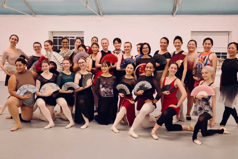 Group of dancers holding fans in a studio