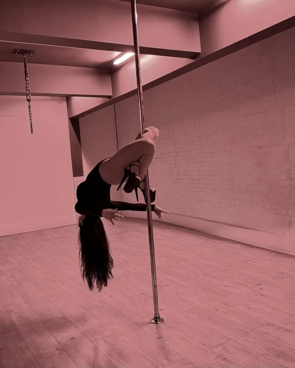 Person performing a pole dance move indoors
