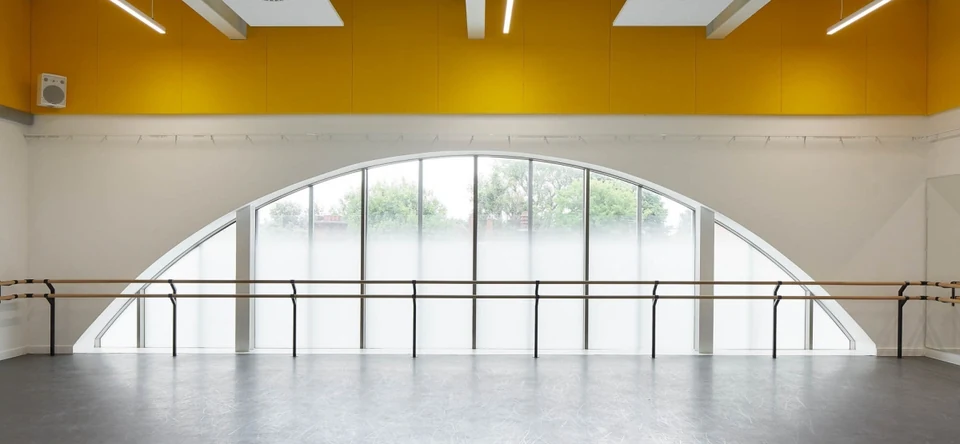 Dance studio with large arched windows and wooden ballet barres