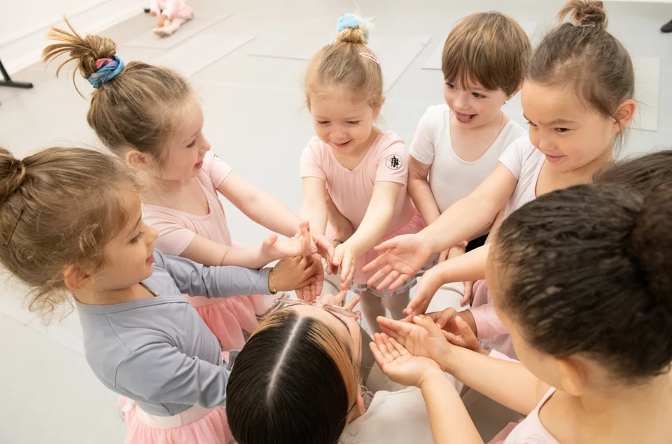 Children in ballet attire interacting in a dance studio
