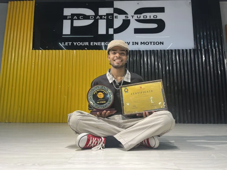 Person sitting on floor with awards in dance studio