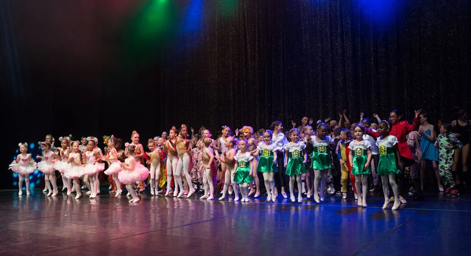 Children performing in colorful costumes on stage