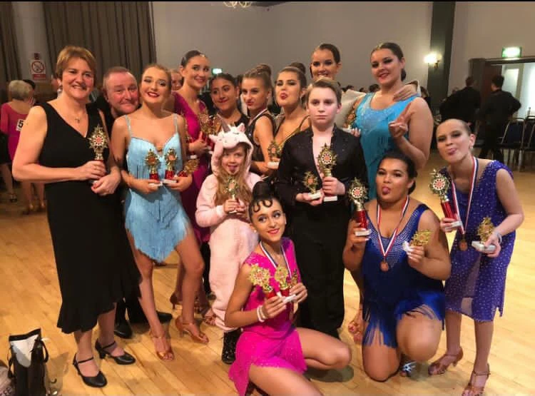 Group of dancers holding trophies at an event