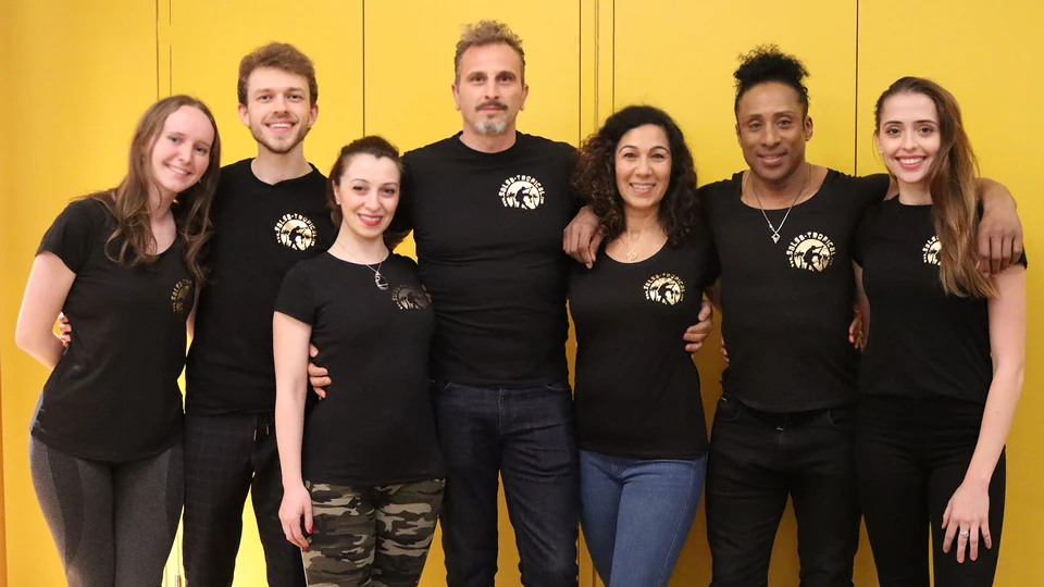 Group of dancers posing in black shirts