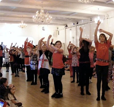 Children dancing in a studio with raised hands