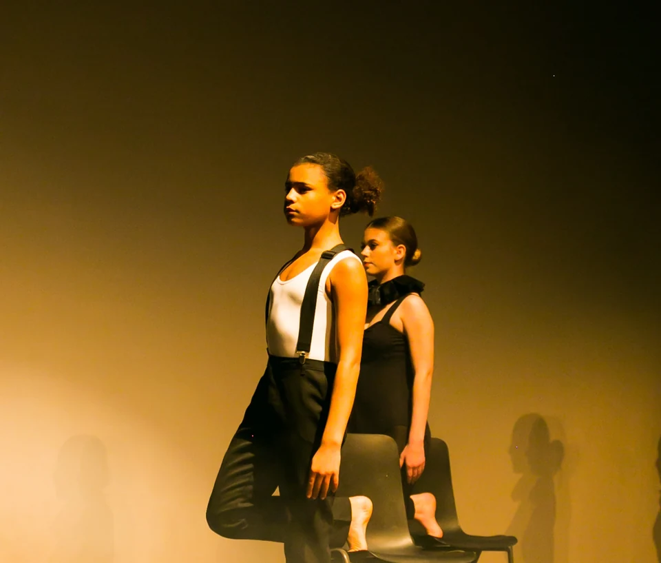 Two dancers performing on stage in black attire