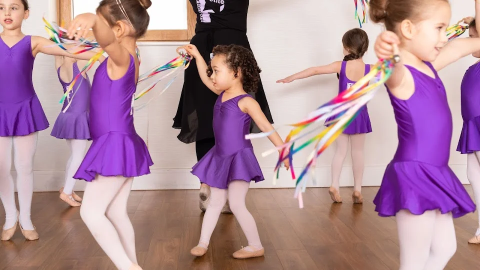 Children dancing in purple costumes with ribbons