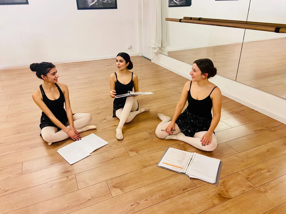 Three ballet dancers in a studio discussing notes