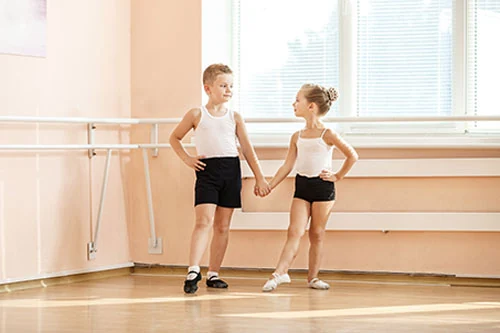 Two children holding hands in a dance studio