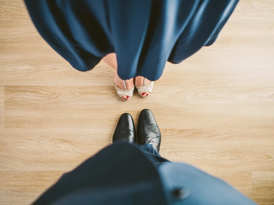 Couple's feet in formal attire on wooden floor