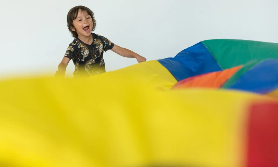 Child playing with colorful parachute fabric