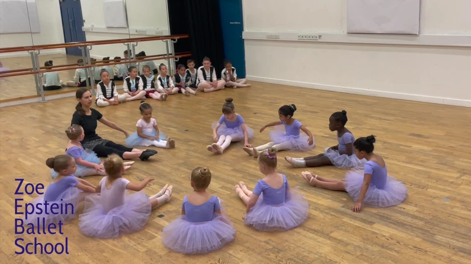 Children in ballet attire sitting on the floor